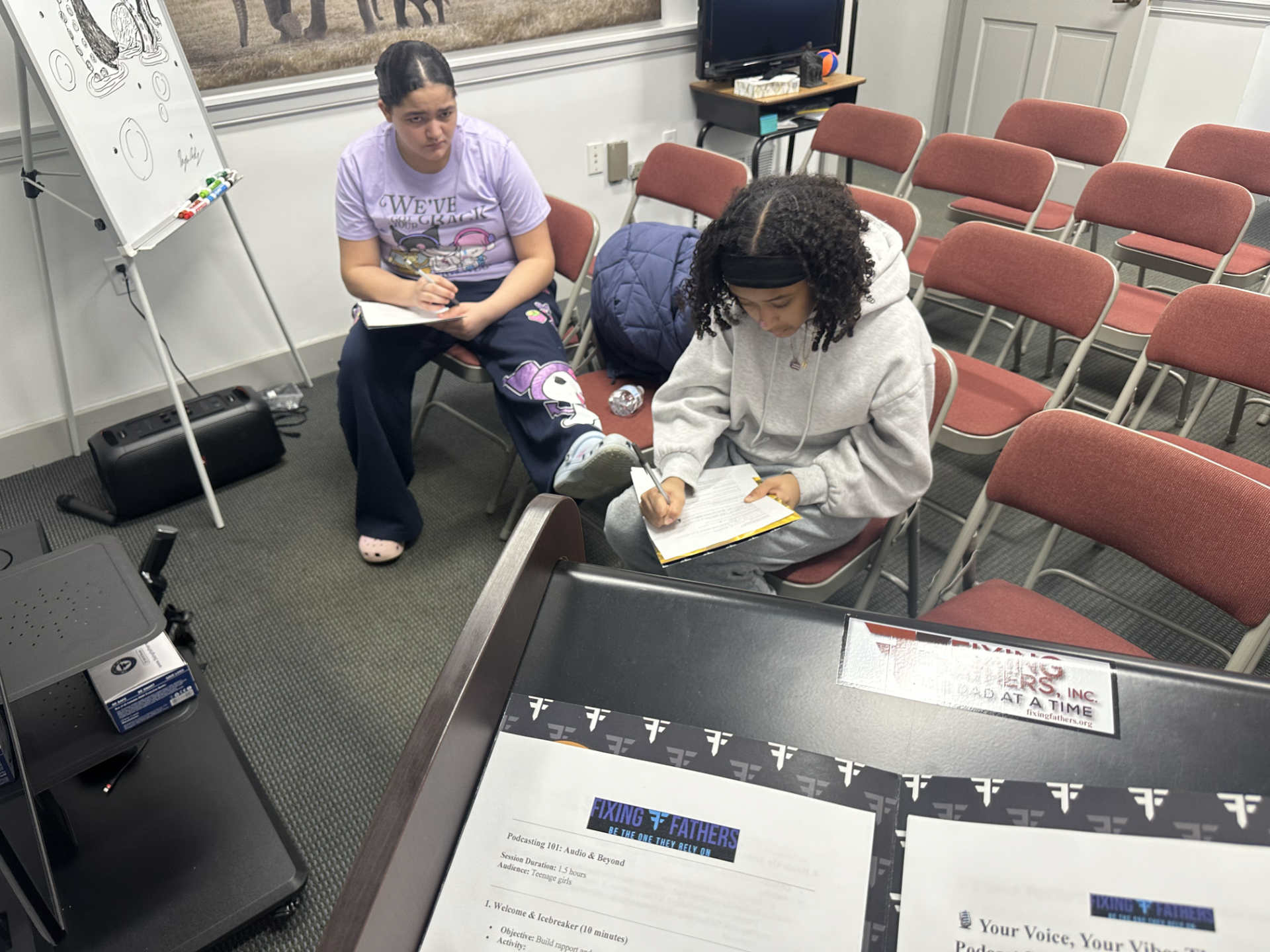 Young participants writing during a podcasting workshop